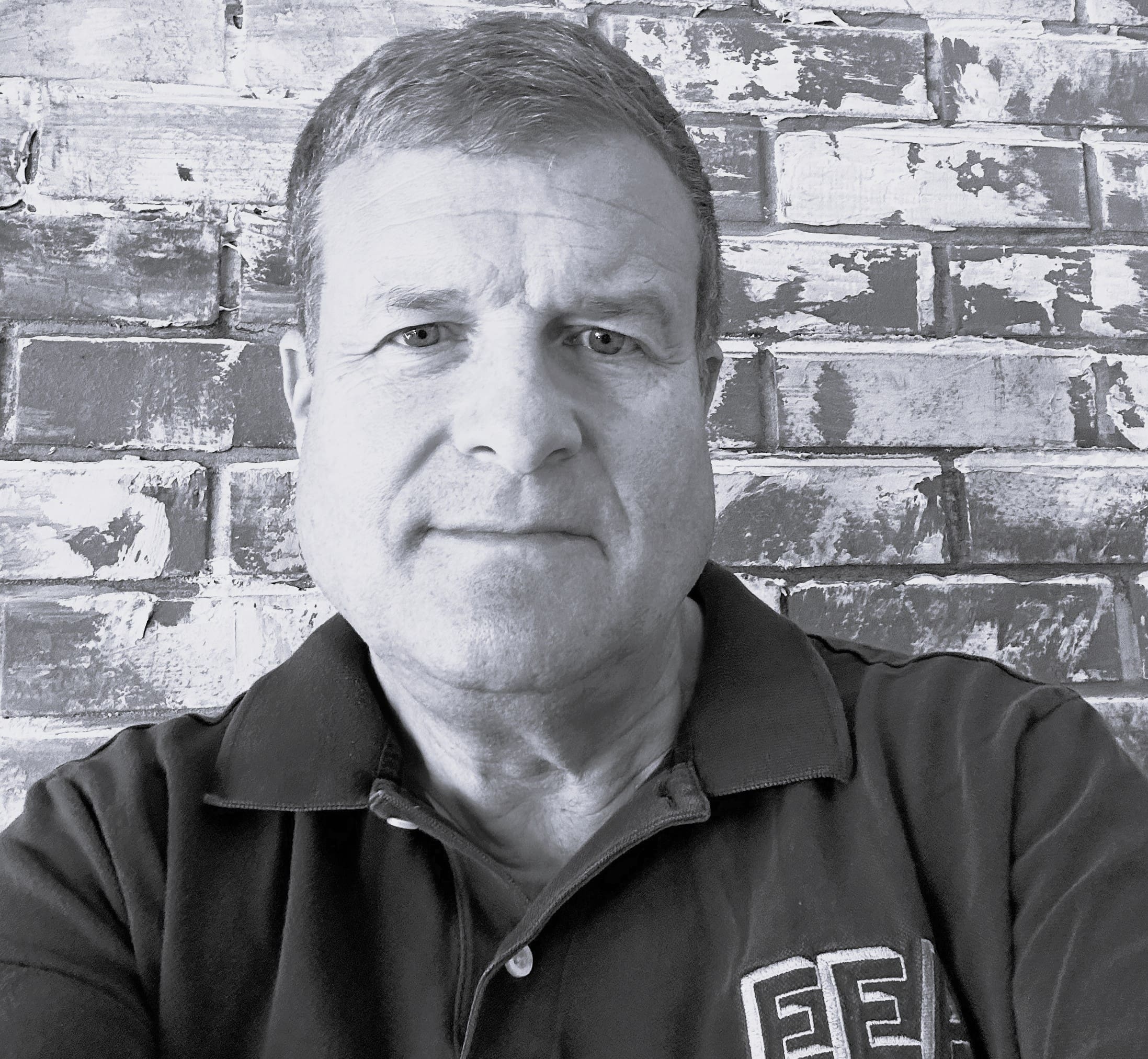 Person in black shirt against a brick wall background.
