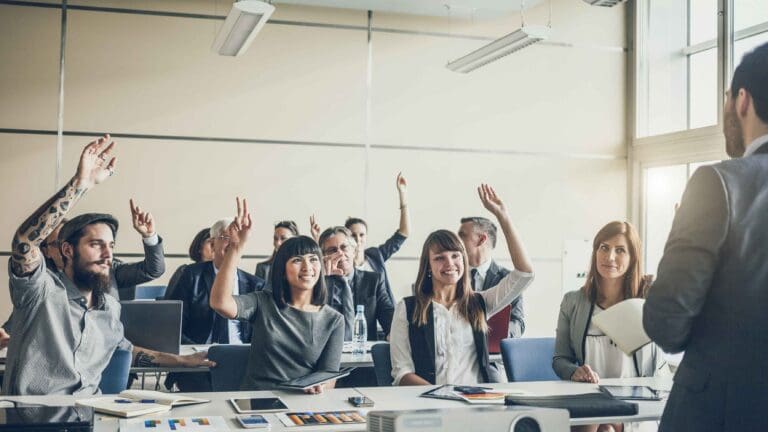 People raising hands in a professional meeting.