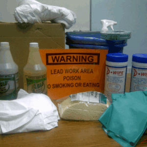 Lead work area warning sign with cleaning supplies and protective gear on a table.