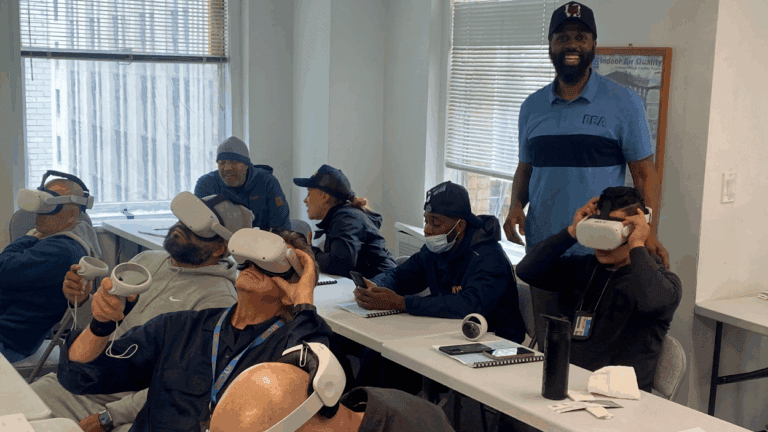 People using VR headsets in a classroom setting, overseen by an instructor.