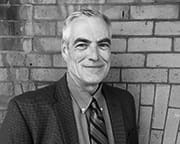 Senior professional smiling against brick wall.