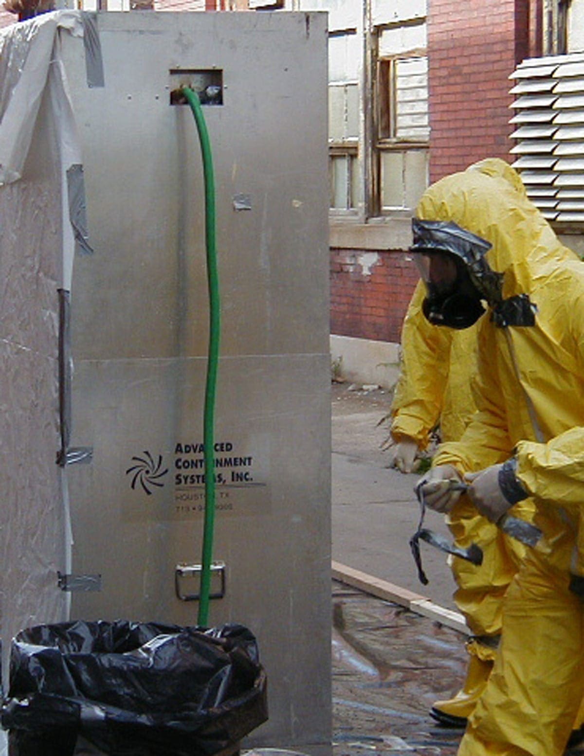 Person in protective suit working with industrial equipment outdoors.
