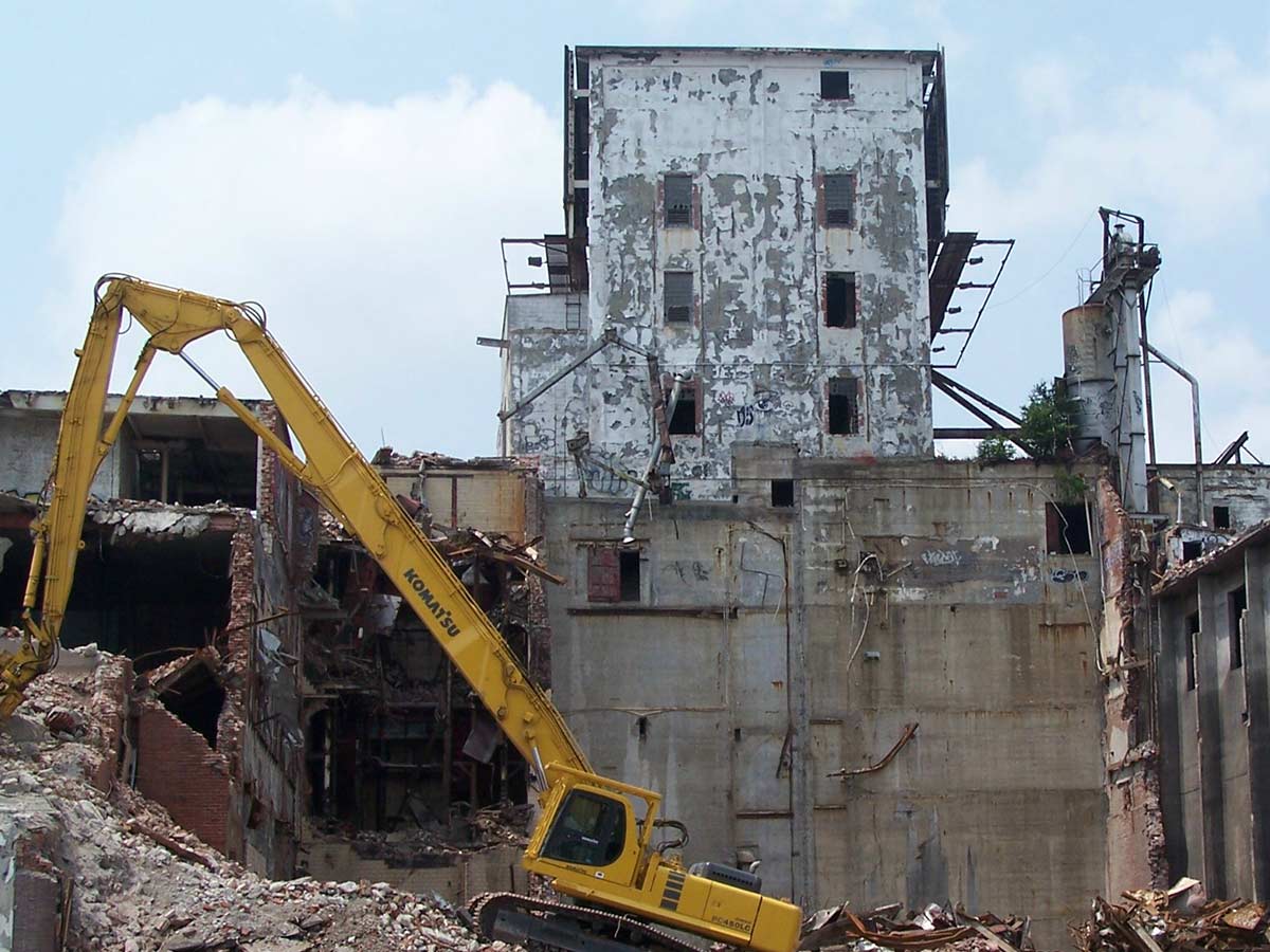 Industrial building demolition with excavator.