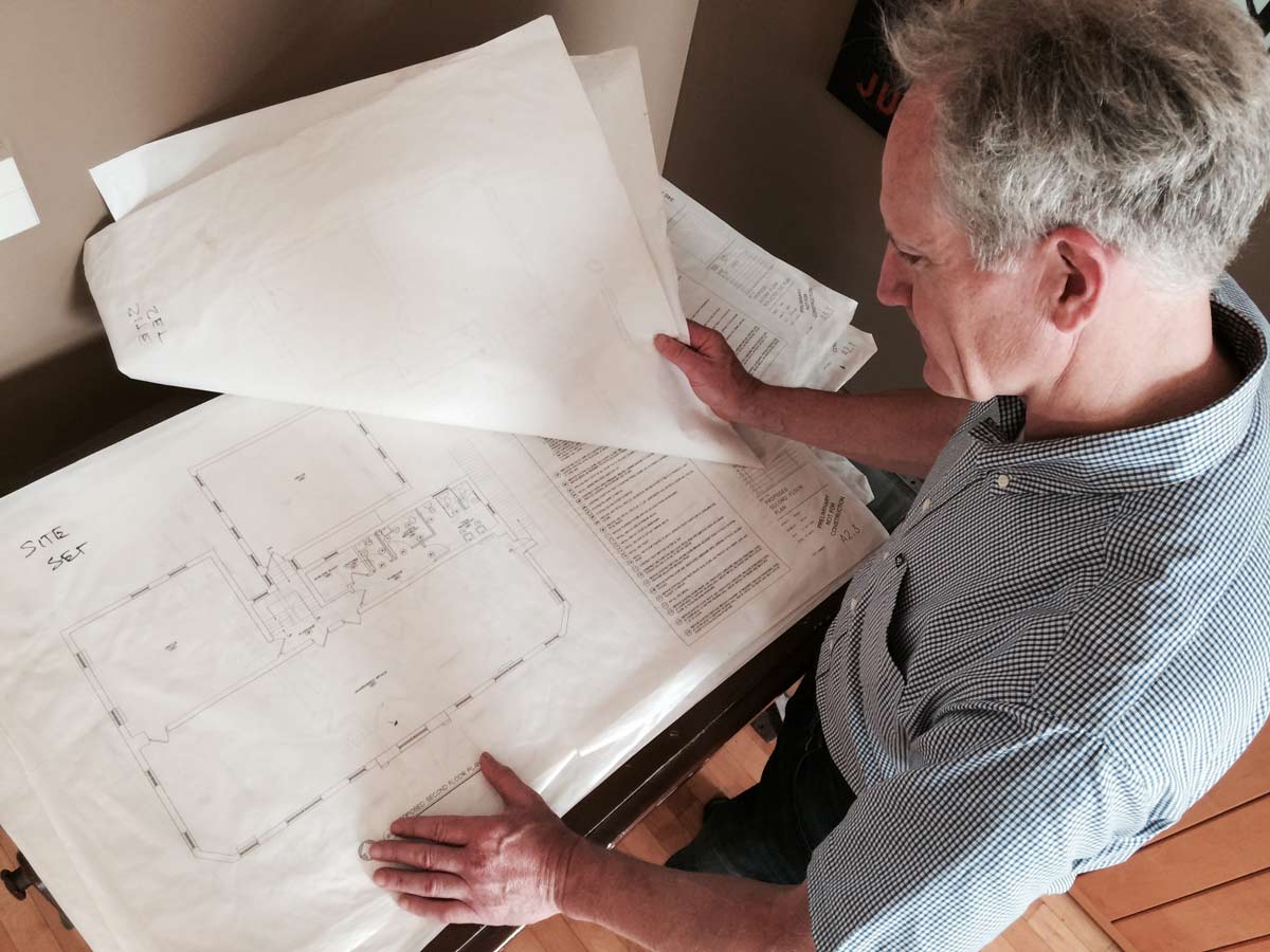 Man reviewing architectural plans at a desk.