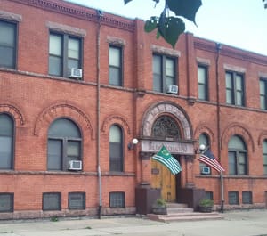 Historic brick building with two flags by the entrance.