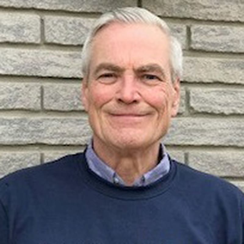 Man smiling against a brick wall background.