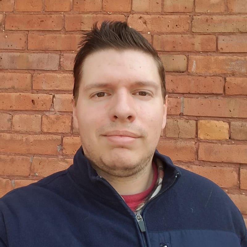 Person standing against a brick wall background.