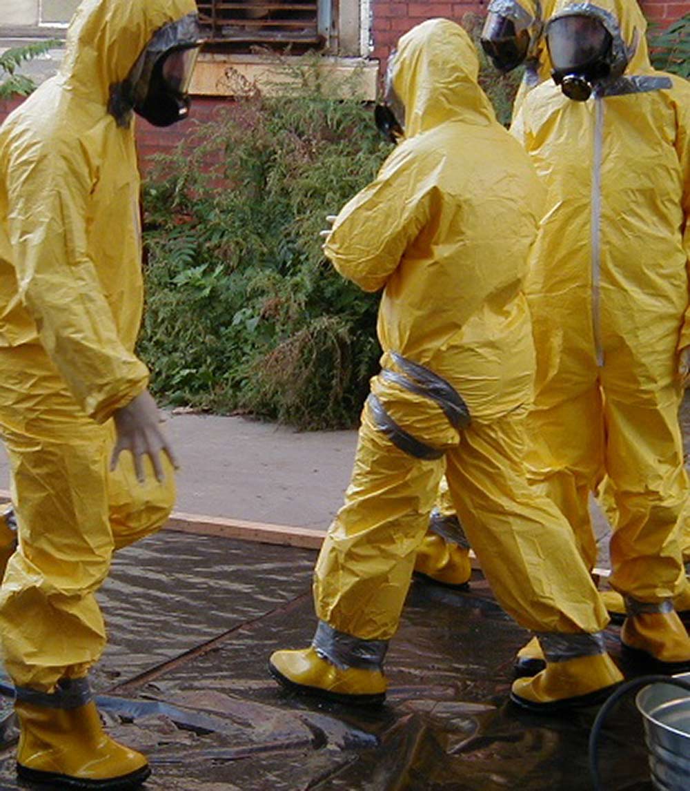People in yellow hazmat suits working outdoors.