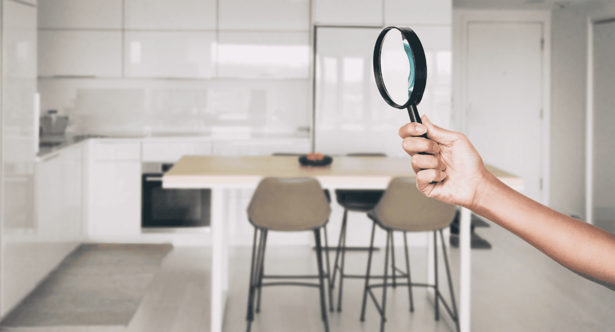 Hand holding magnifying glass in modern kitchen.