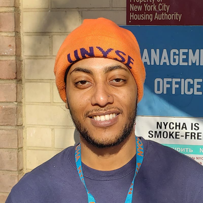 Person standing outside New York City Housing Authority office smiling.