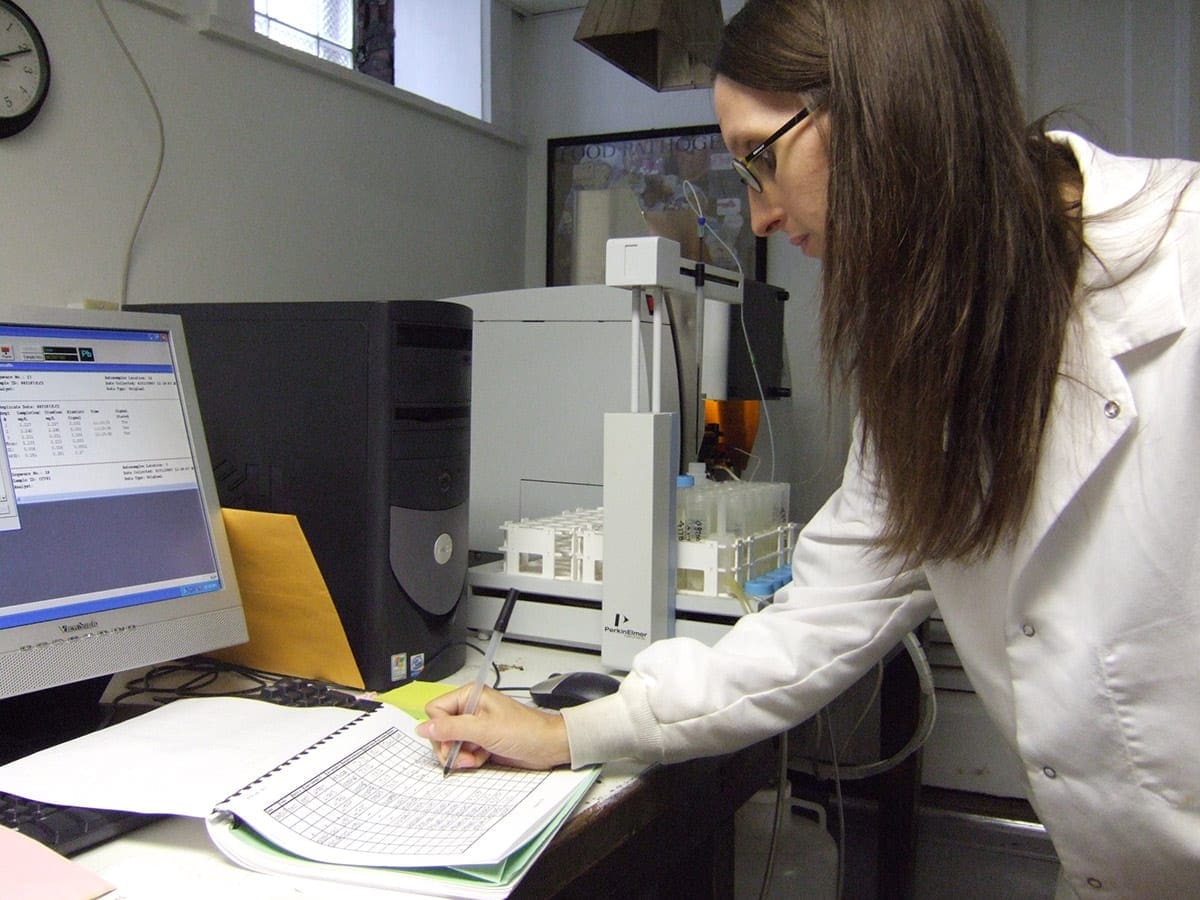 Lab technician analyzing data on a computer in a research setting.