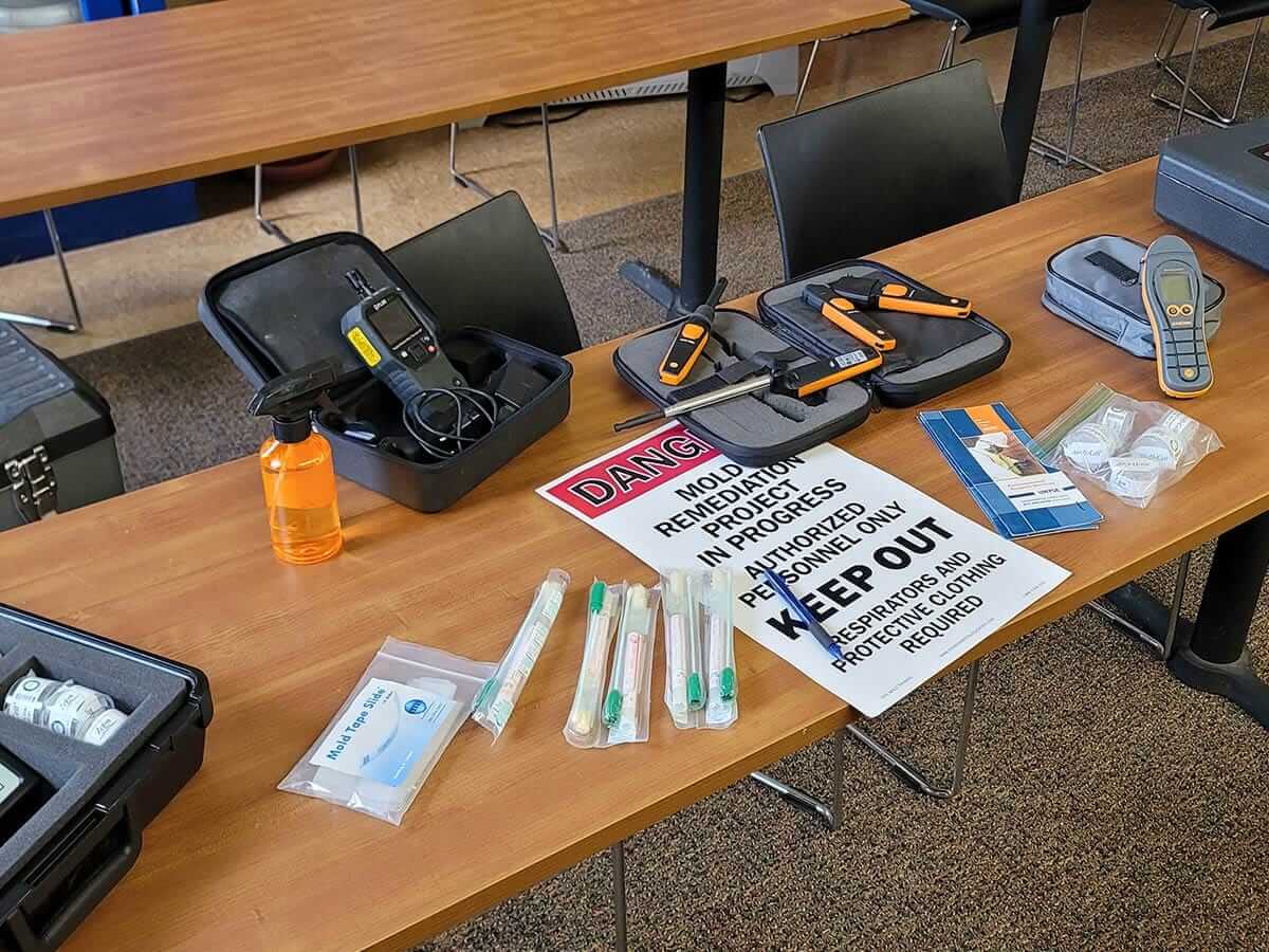 Mold remediation tools and warning sign on a table.