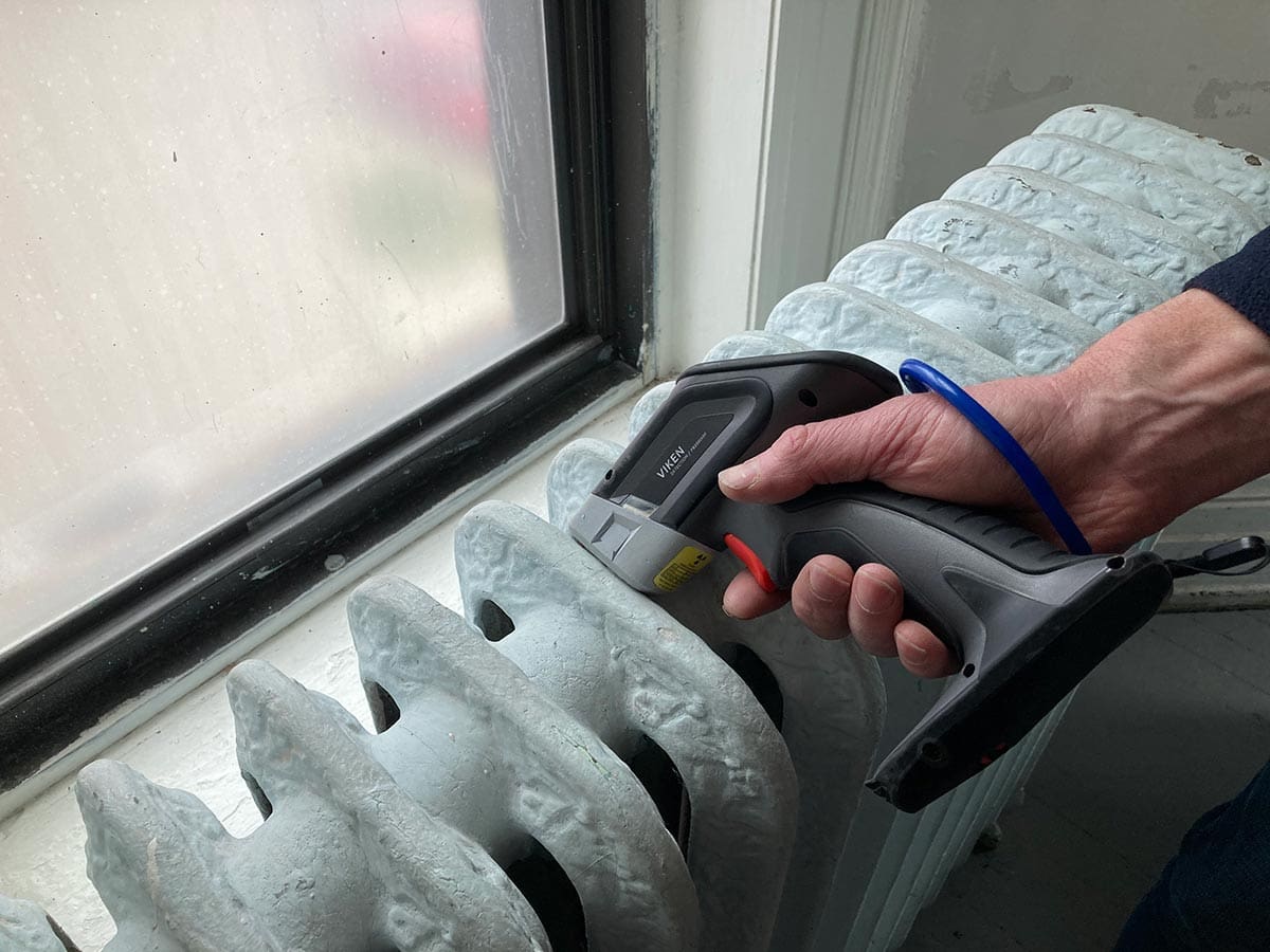 Thermal camera checking radiator temperature near window.