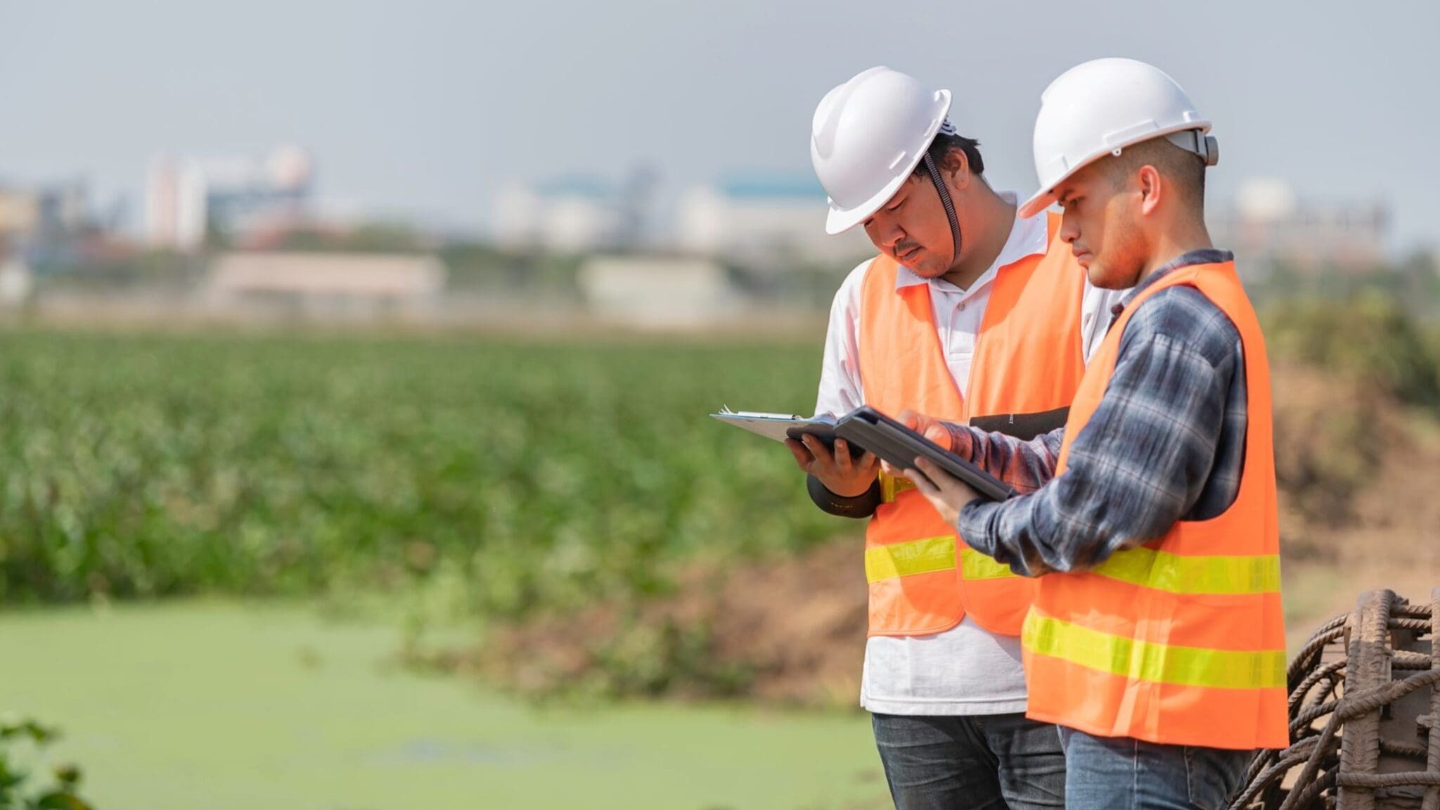 Two construction workers reviewing plans at a site.
